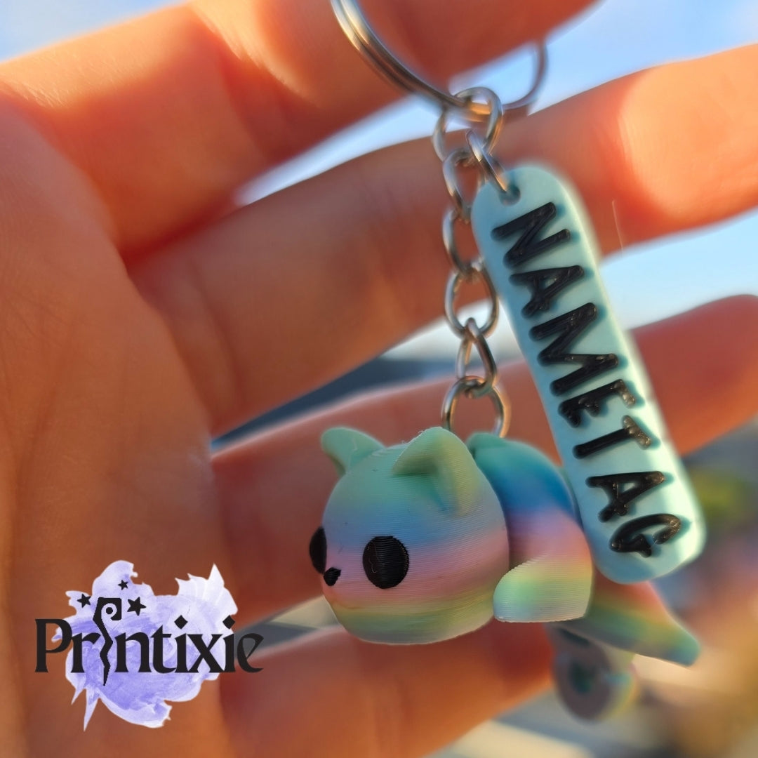 Rainbow 3D printed tiny cat keychain with nametag, made by Printixie