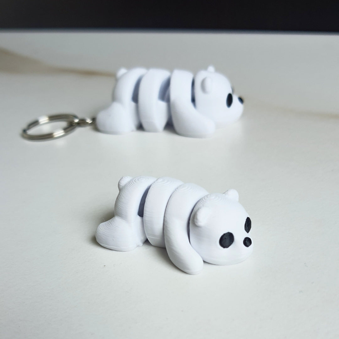 Two small 3D printed white polar bear toys with black eyes, designed as keychains or desk decorations.