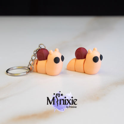 Two 3D printed snail keychains with articulated joints, on a marble surface
