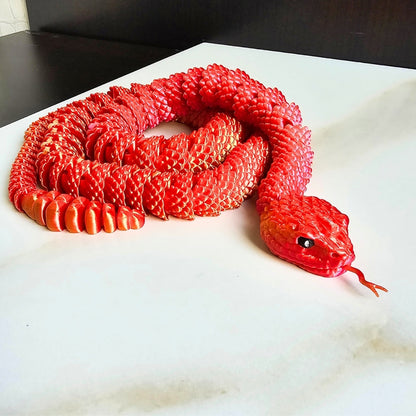 3D printed red and yellow snake toy on a white surface.