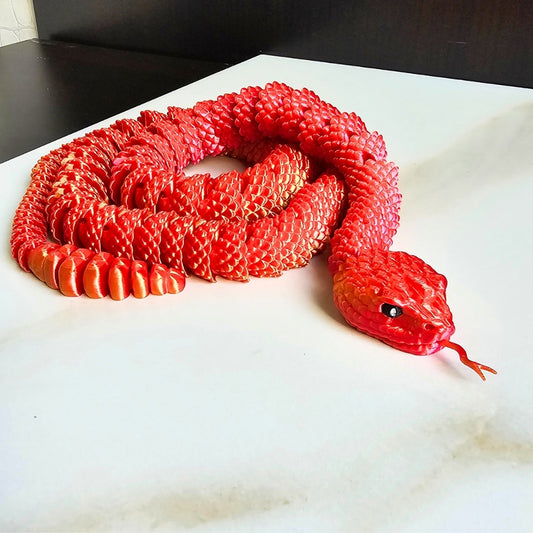 3D printed red and yellow snake toy on a white surface.