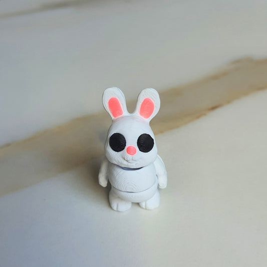 A 3D printed white standing bunny toy with black eyes and pink nose and ears, balancing upright on two feet.